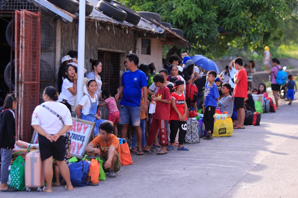 Residents wait for a ride along the road after the local government implemented a preemptive evacuation in Legazpi, Albay on November 15, 2024