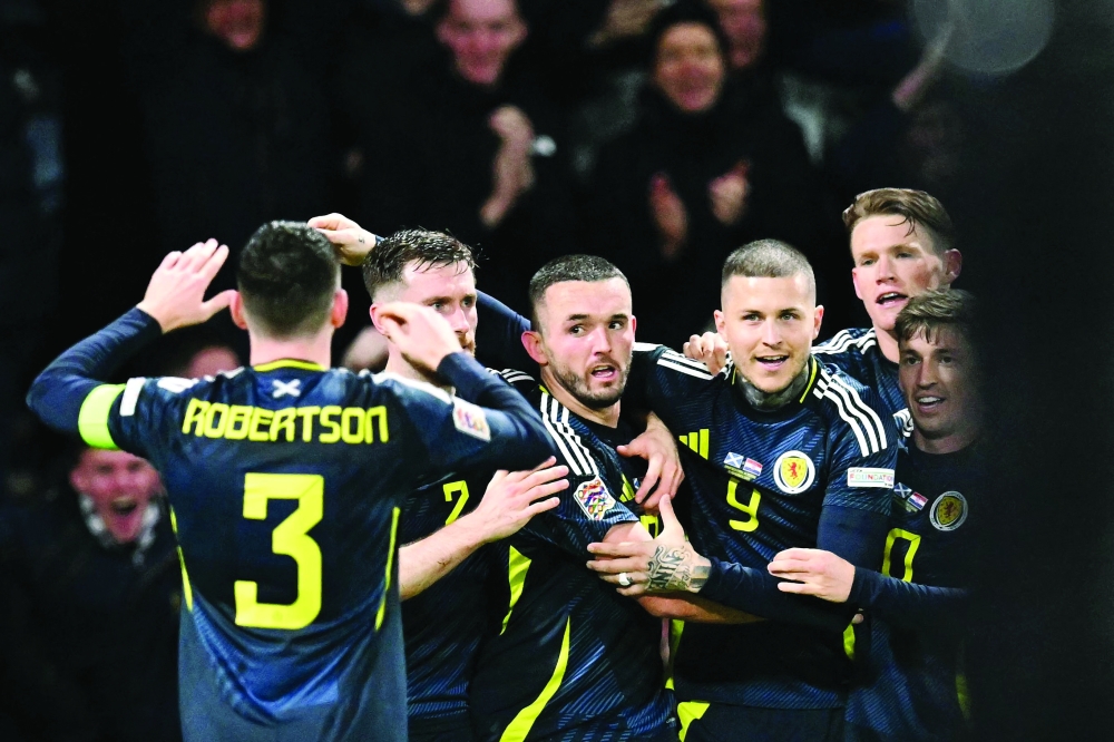 Scotland's John (C) celebrates scoring first goal. — AFP