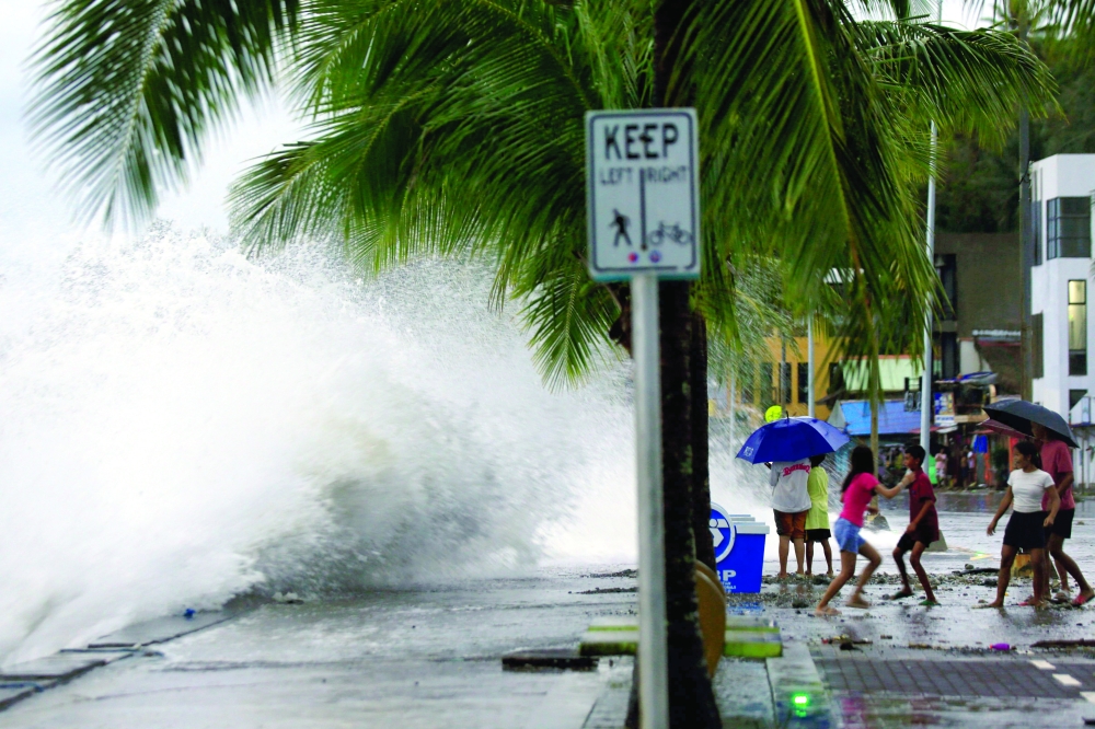 People react as large waves break along a seawall ahead of the expected landfall of Super Typhoon Man-yi in Legaspi City, Albay province. - AFP