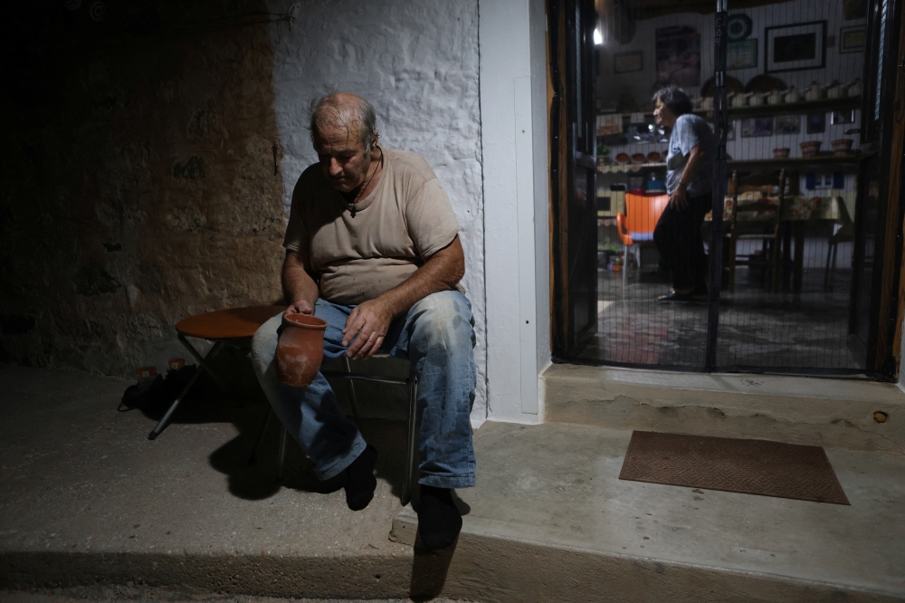Nikos Kouvdis, 70, sits outside in his family’s pottery workshop in Agios Stefanos village, near Mandamados on the Greek island of Lesbos, Greece, July 21, 2024. His family’s dedication to preserving the craft was recently honored with inclusion in UNESCO’s National Inventory of Intangible Cultural Heritage. REUTERS/Elias Marcou
