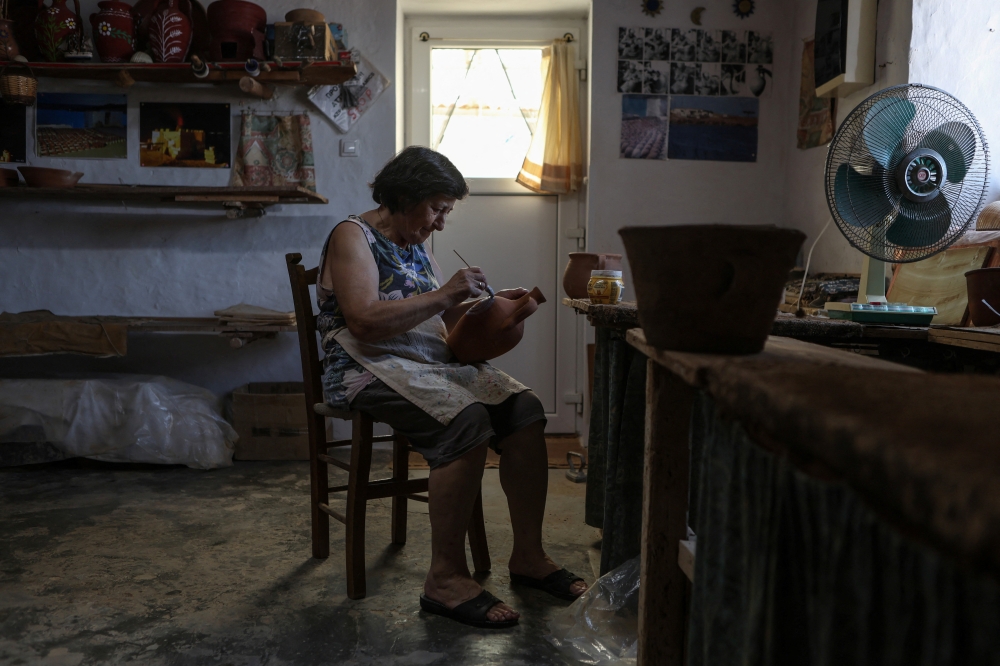 Paraskevi Kouvdi hand paints a ready item in the pottery workshop in Agios Stefanos village, near Mandamados on the Greek island of Lesbos, Greece, July 16, 2024. Kouvdis family’s dedication to preserving the craft was recently honored with inclusion in UNESCO’s National Inventory of Intangible Cultural Heritage. REUTERS/Elias Marcou
