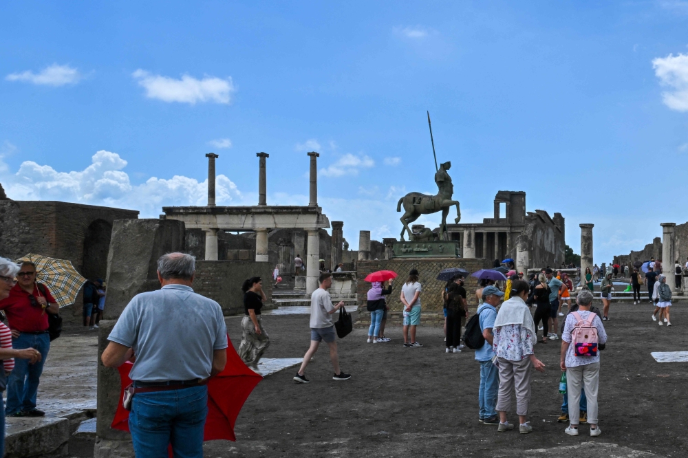 Visitors tour the Archaeological Park of Pompeii, near Naples, southern Italy, on June 9, 2022. Daily cap of 20,000 visitors to archaeological park comes into effect today on November 15, 2024.  (Photo by Andreas SOLARO / AFP)


