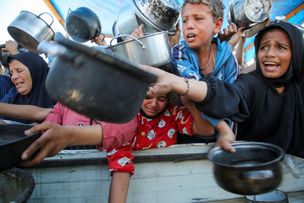 Palestinians gather to receive food cooked by a charity kitchen, amid a hunger crisis, in Khan Younis. — Reuters 