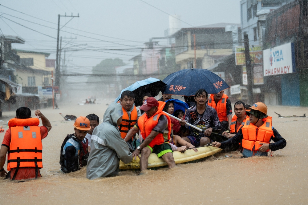 FILE PHOTO: Rescuers assist residents on a boat as they wade through a flooded road following heavy rains brought by Typhoon Gaemi, in Marikina City, Metro Manila, Philippines, July 24, 2024. REUTERS/Lisa Marie David/File Photo
