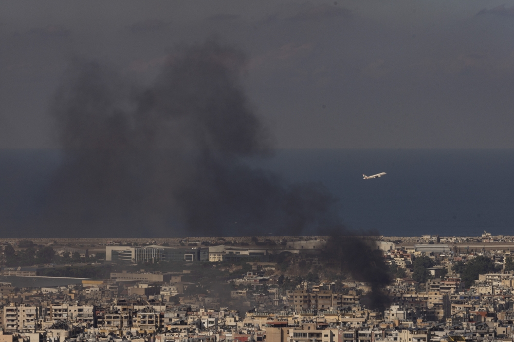 A Middle East Airlines flight takes off from Rafic Hariri A Middle East Airlines flight over the outskirts of Beirut, Lebanon on Friday, Oct. 4, 2024, as smoke rose from Israeli airstrikes overnight. (David Guttenfelder/The New York Times)