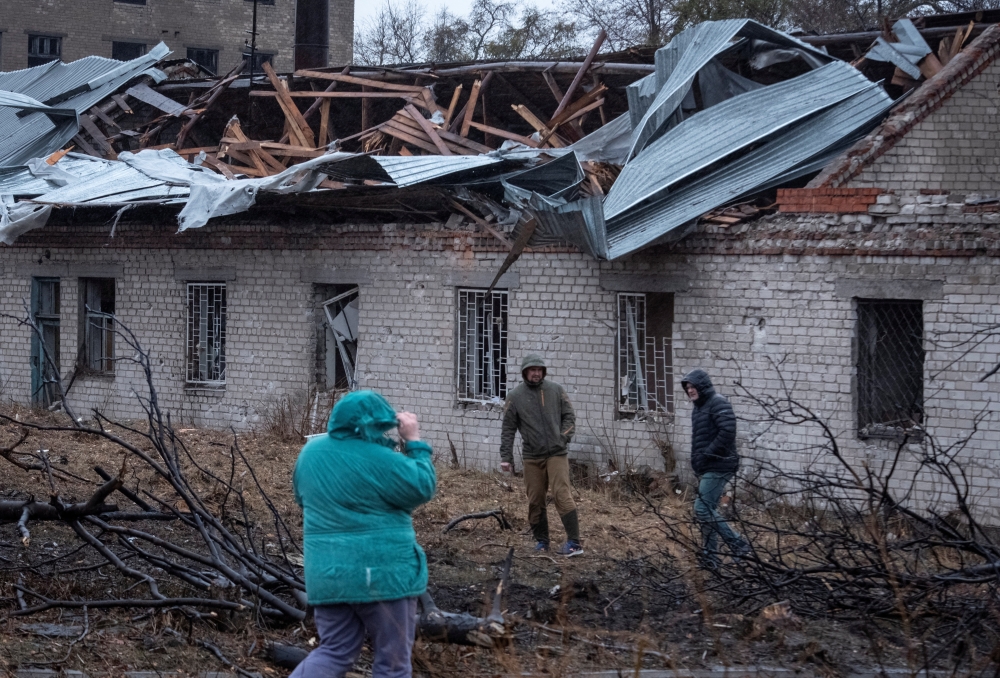 Residents walk at a site of a Russian missile strike, amid Russia's attack on Ukraine
