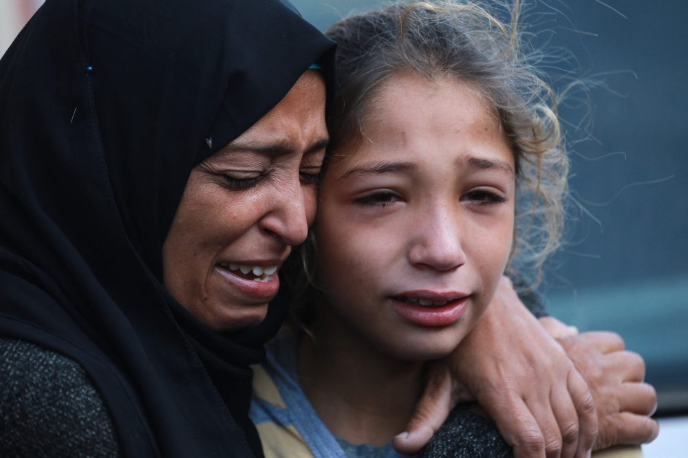 A Palestinian woman and child cry outside the al-Aqsa Martyrs Hospital in Deir el-Balah where victims of an Israeli strike 