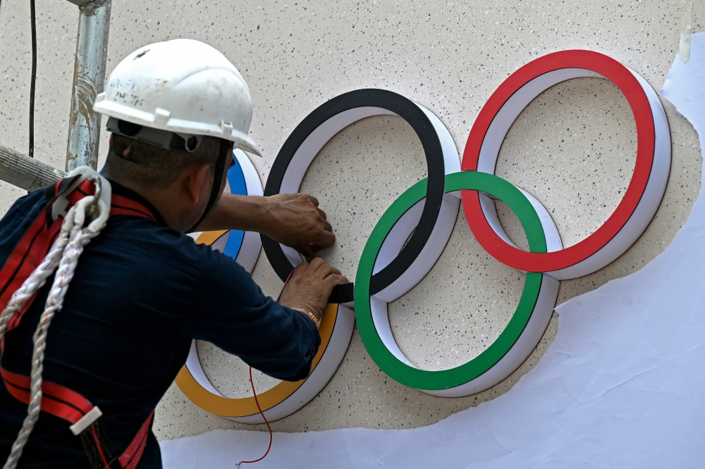 A laborer fixes the Olympic signage at the entrance of a venue ahead of the 141st International Olympic Committee (IOC) session in Mumbai