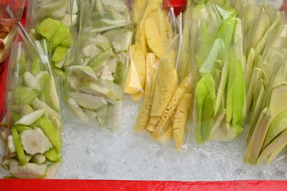 Fresh fruits are kept for sale in single-use plastic bags at a streetside stall in Bangkok 