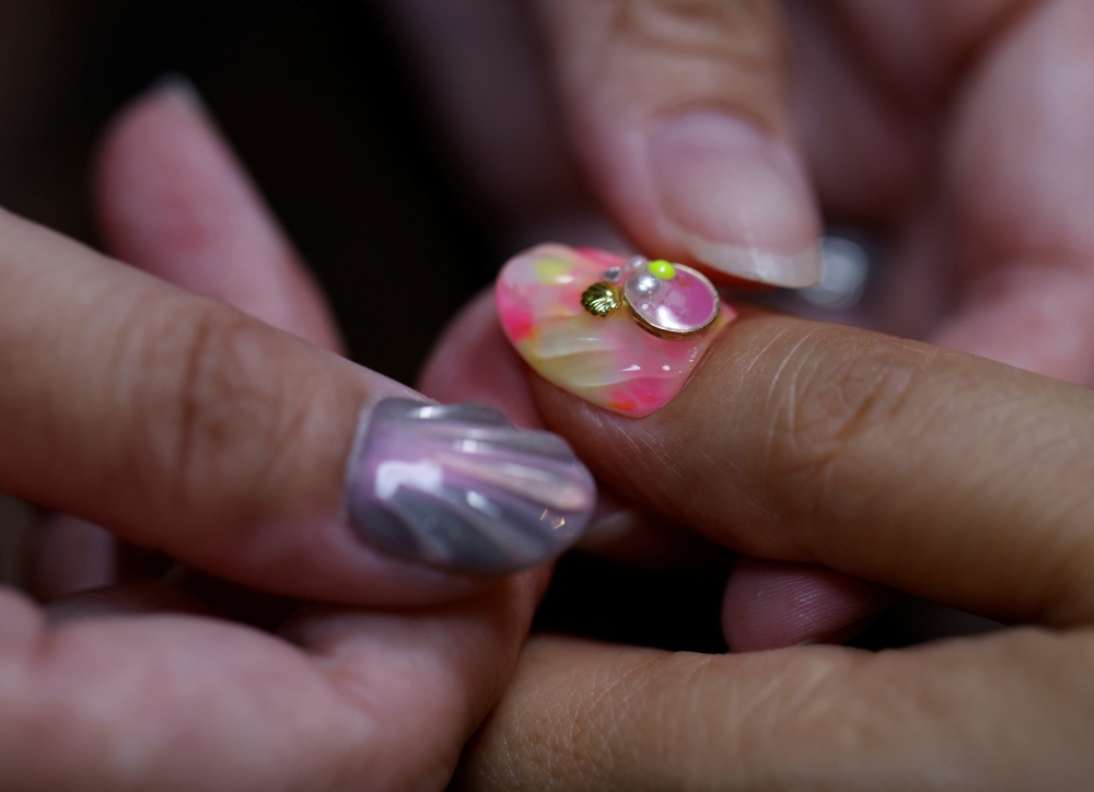 Japanese manicurist Naomi Arimoto presses a false nail with a decorative nail tip using plastic waste which she collected from the beach, onto a thumb of a customer at her nail salon in Chigasaki, Kanagawa Prefecture, Japan October 21, 2024. REUTERS/Manami Yamada
