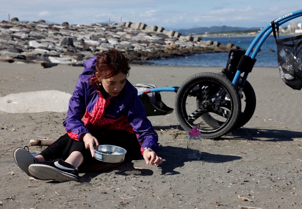 Japanese manicurist Naomi Arimoto collects plastic waste from the sand at a beach in Chigasaki, Kanagawa Prefecture, Japan, October 21, 2024. REUTERS/Manami Yamada
