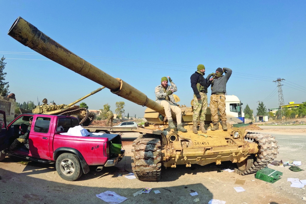 Fighters seize a Syrian Army tank on the international M5 highway in Zarbah which was taken over by anti-government factions as fighters and allied groups continue their offensive in Syria's northern Aleppo province against government forces. - AFP