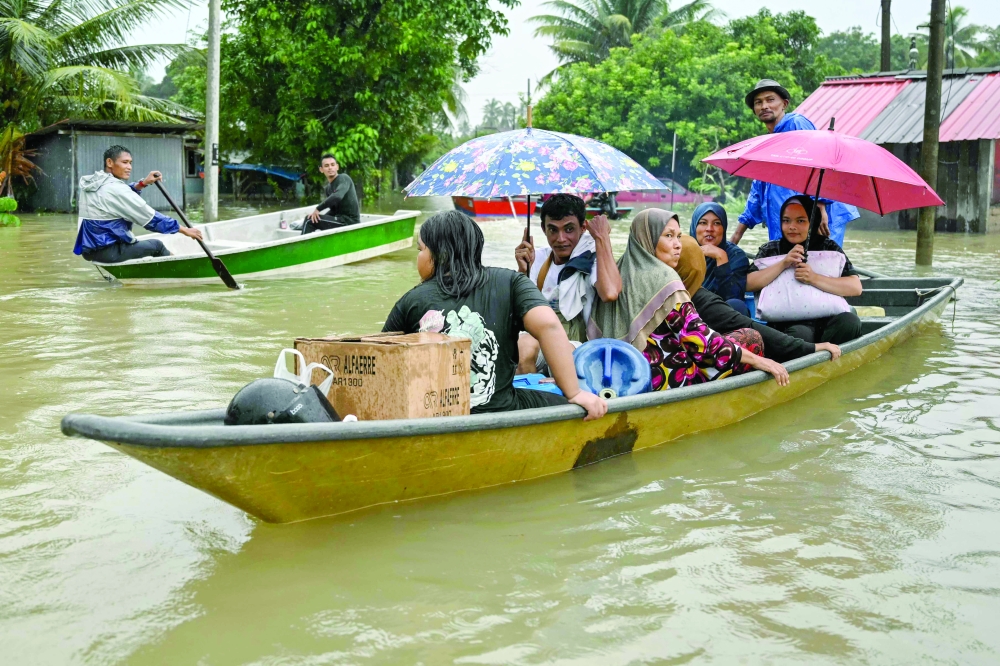 Residents are transported on boats through flood waters after days of heavy rain in Tumpat in Malaysia's Kelantan state. — AFP