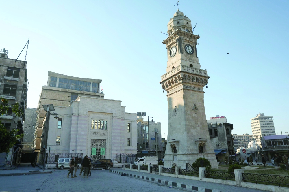 Fighters stand next to the clock tower of Aleppo's National Library, Syria. — AFP