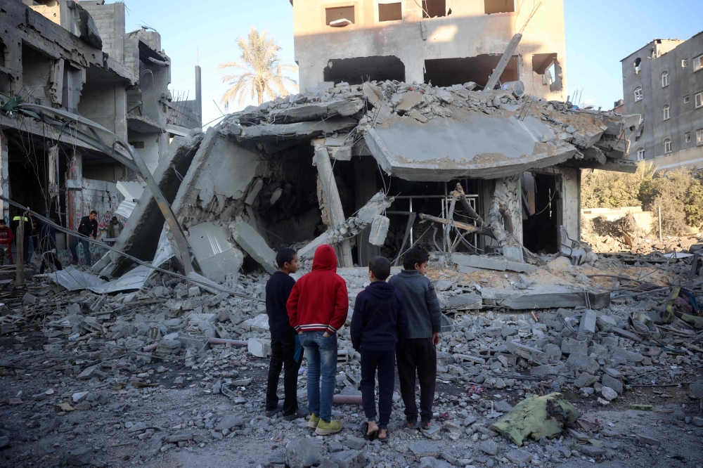 Palestinian children stare at a building destroyed in an Israeli airstrike in Nuseirat in the central Gaza Strip. — AFP 