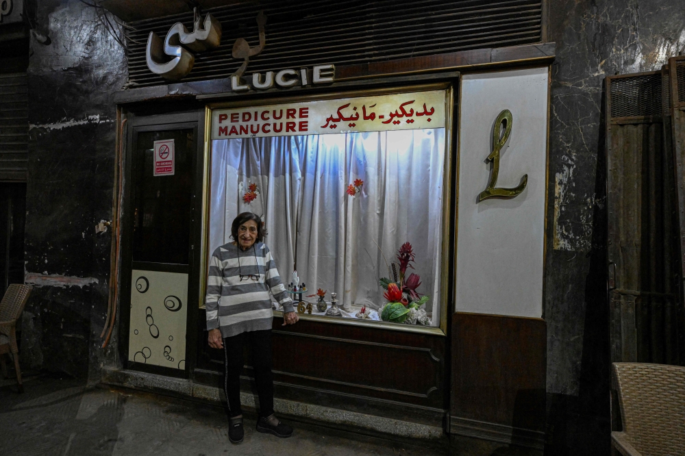 Madam Lucie, an 88-year-old manicurist expert, poses for a picture at her manicure shop in downtown Cairo on November 18, 2024. Nestled in a hidden alley off a bustling thoroughfare in the heart of the Egyptian capital sits an unassuming little manicure shop concealing a historic legacy. But decades ago, the shop's seats were occupied by the likes of Nobel laureate Naguib Mahfouz, international singing sensation Dalida and cinematic heartthrob Omar Sharif, all of whom sought the now 88-year-old manicurist's expert hand. (Photo by Khaled DESOUKI / AFP)

