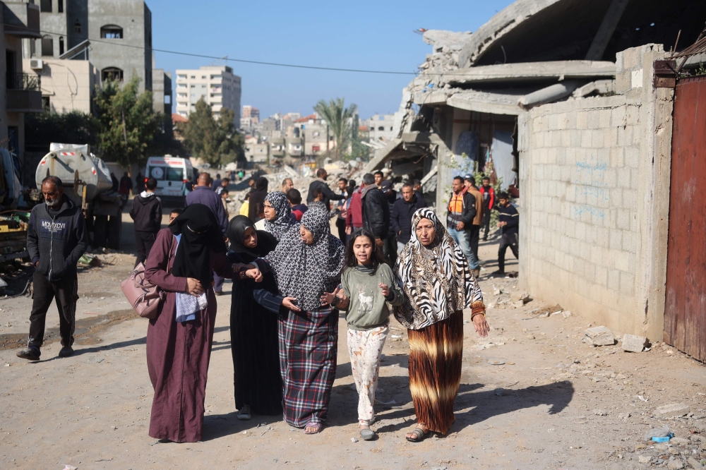 Palestinians walk past a damaged house in the Bureij refugee camp in the central Gaza Strip. — AFP