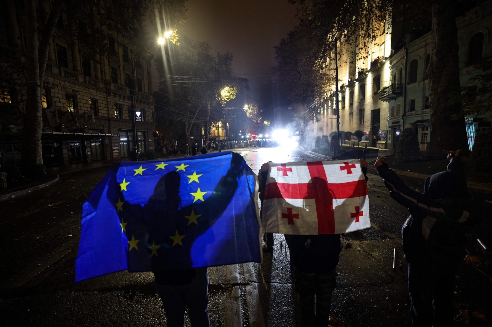 Protesters hold up a European Union and Georgian flags during the fifth straight night of demonstrations against the government's postponement of EU accession talks until 2028, in central Tbilisi early 