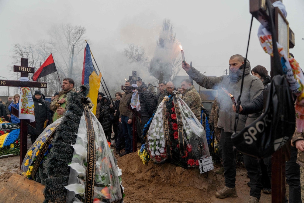 Mourners hold smoke flares during a funeral ceremony, at a cemetery in Kyiv. — AFP 