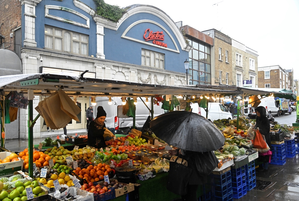 Customers shop at a fruit and vegetable stall at Portobello Road in London. — Reuters