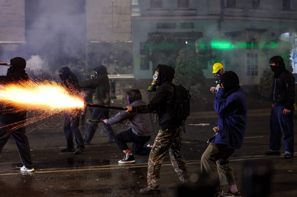 Anti-government protesters launch fireworks towards police during mass demonstrations, in central Tbilisi. — AFP 