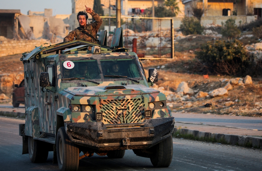 A rebel led by the Hayat Tahrir Al Sham group stands in the back of a vehicle in Al Rashideen, Aleppo province, Syria. — Reuters