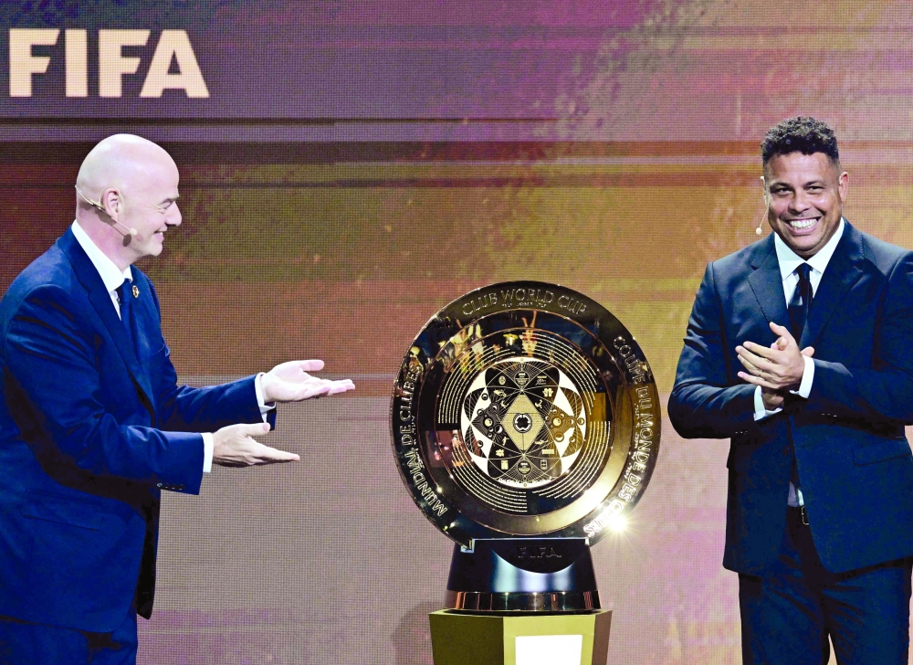 Fifa President Gianni Infantino (L) and Brazilian former soccer player Ronaldo unveil the trophy during the 2025 Fifa Club World Cup Draw ceremony in Miami.