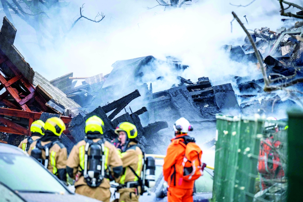 Firemen stand next to a partially collapsed residential building following a fire and an explosion in The Hague. — AFP 