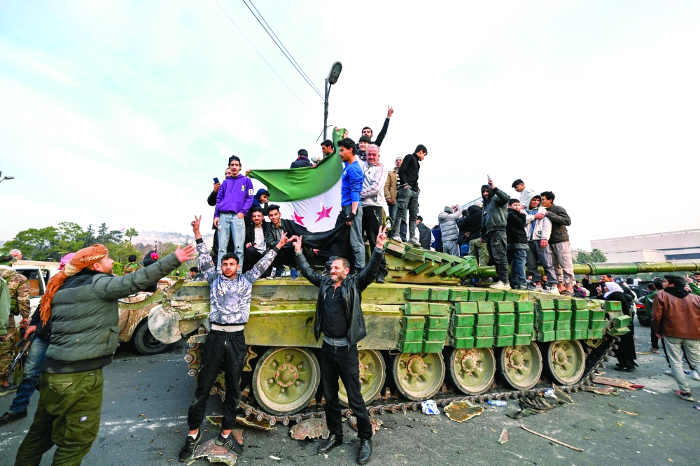 People celebrate with anti-government fighters at Umayyad Square in Damascus. — AFP