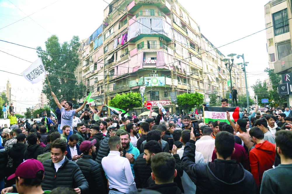 Syrians celebrate the taking over of the capital Damascus by Syrian rebel fighters in Beirut's Triq al Jdideh neighbourhood. — AFP
