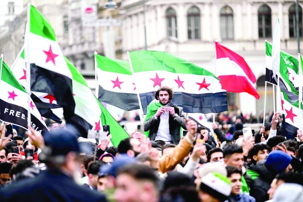 Members of the Syrian community wave Syrian flags in Vienna, Austria. — AFP 