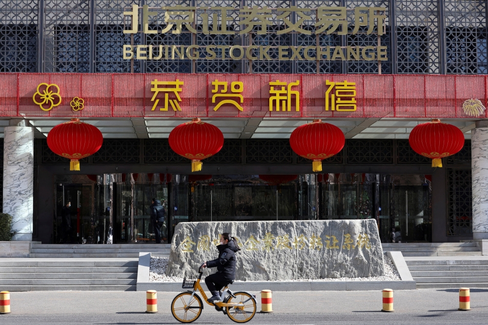 A woman cycles past the Beijing Stock Exchange building in Beijing, China. — Reuters