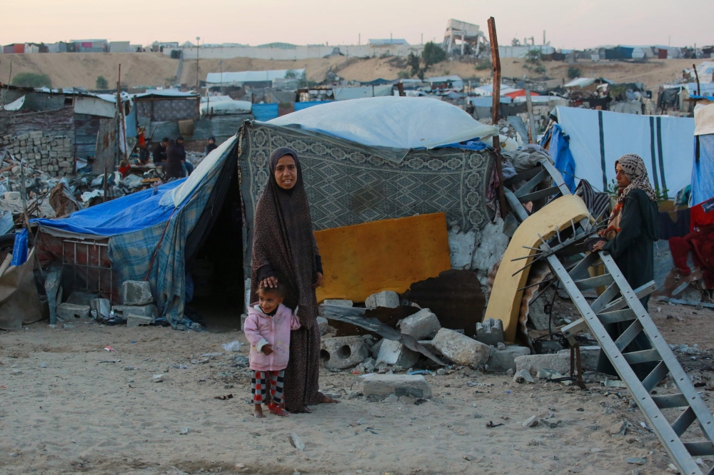 People stand outside their shelters at a makeshift camp for displaced Palestinians in the Nahr al-Bared area. — AFP 