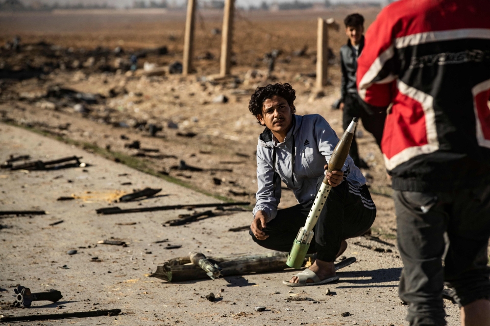 Syrians look for unexploded ammunition at the site of the previous evening's Israeli airstrike, northeastern Syria. — AFP 