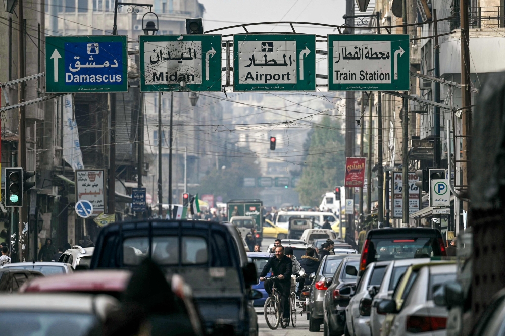 Men ride bicycles through traffic along a street in Syria's northern city of Aleppo. — AFP 
