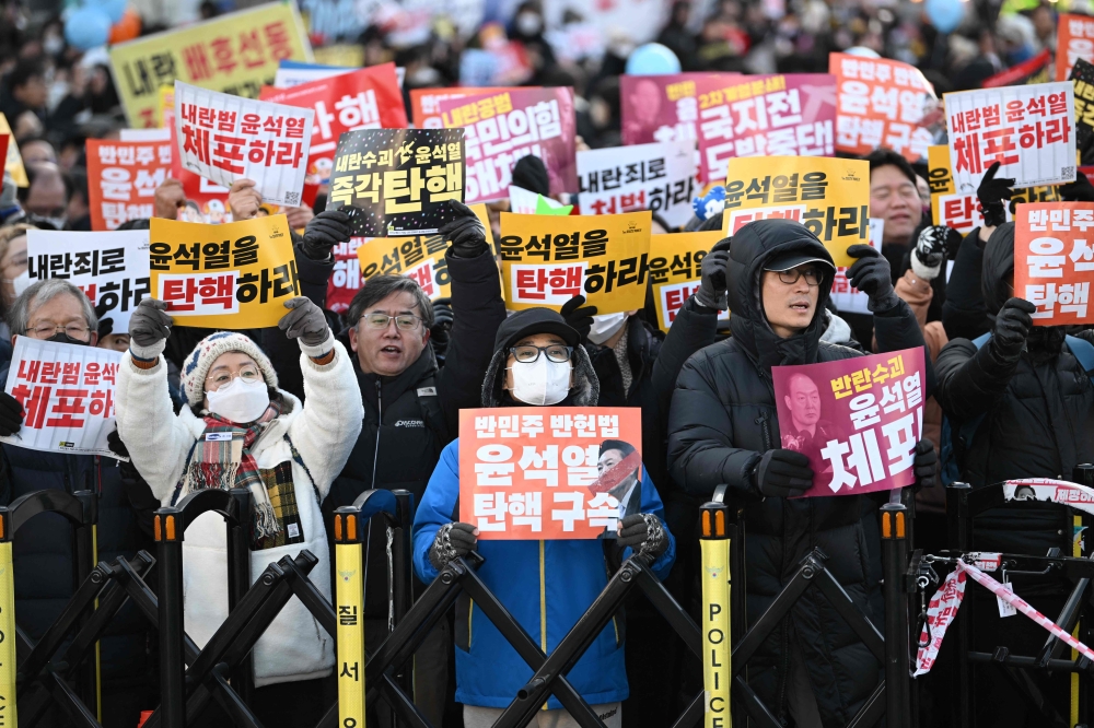 People holding placards reading "Impeach Yoon Suk Yeol" take part in a protest calling for the ouster of South Korea's President Yoon Suk Yeol outside the National Assembly in Seoul on December 14, 2024,