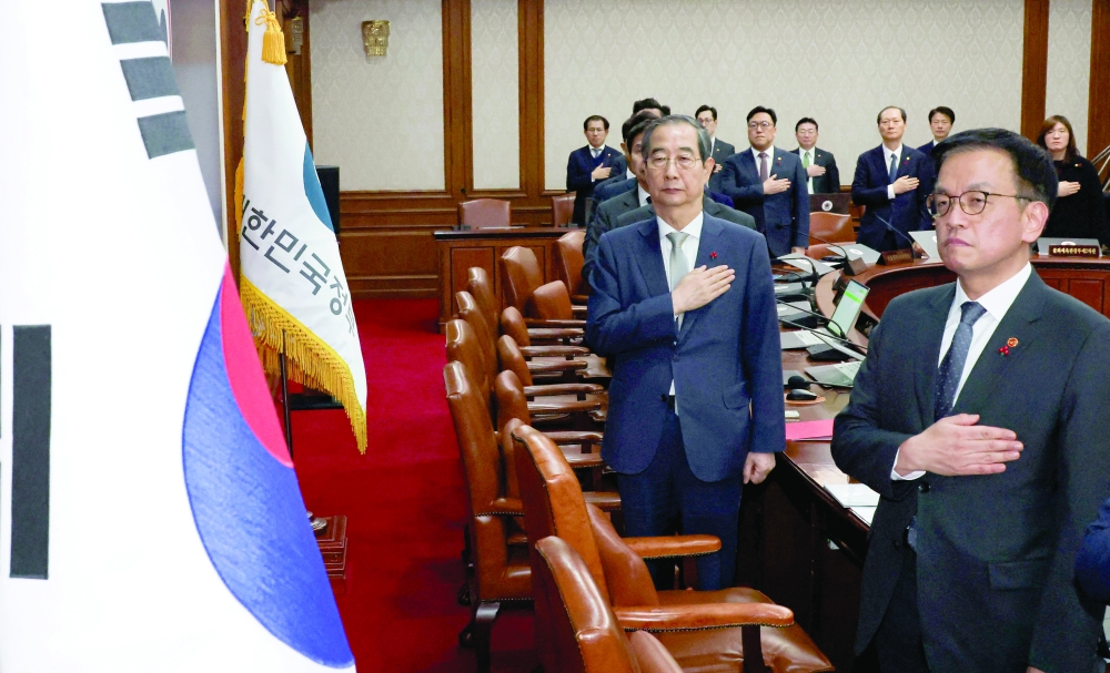 Acting South Korean President and Prime Minister Han Duck-soo salutes to a national flag during a cabinet meeting at the government complex in Seoul, South Korea, on Saturday. — Reuters