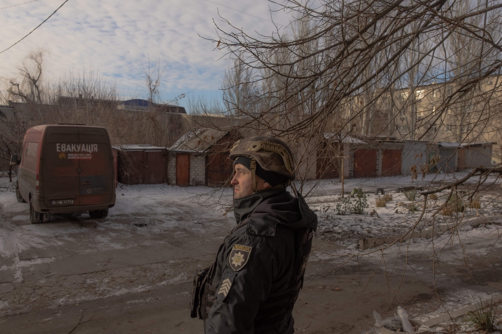 A Ukrainian member of the police looks for drones in the sky during an evacuation of civilians, in the eastern Donetsk region. — AFP 