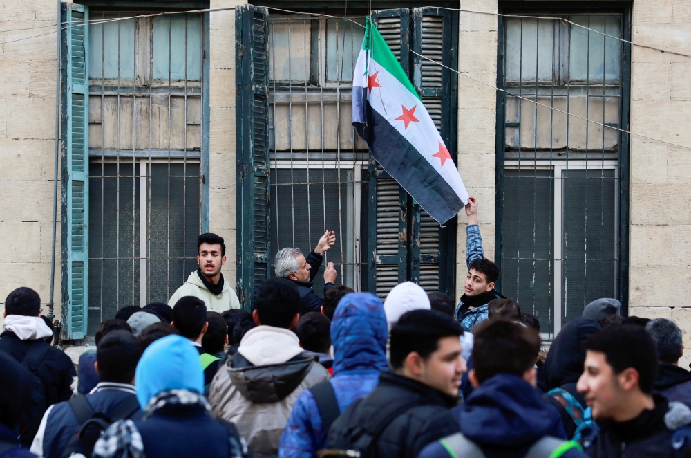 A teacher hoists the new Syrian flag at a school, following an announcement of the reopening of schools, in Damascus, Syria. — Reuters 