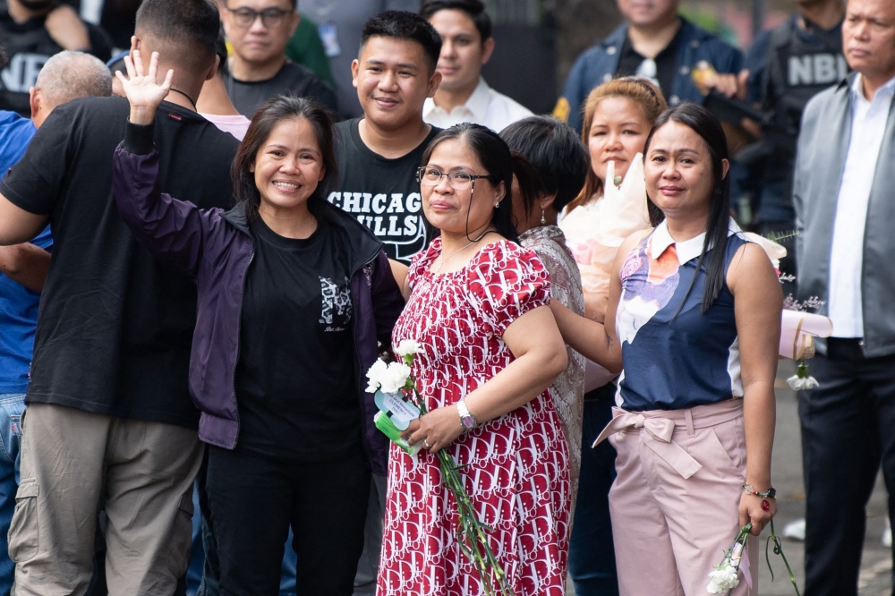 Mary Jane Veloso (L) waves to the media as she meets her family members