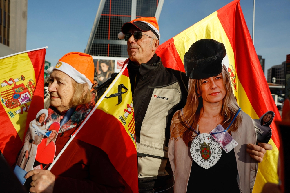 Protestors carry an image of Begona Gomez outside the court where she was questioned, in Madrid. — AFP 