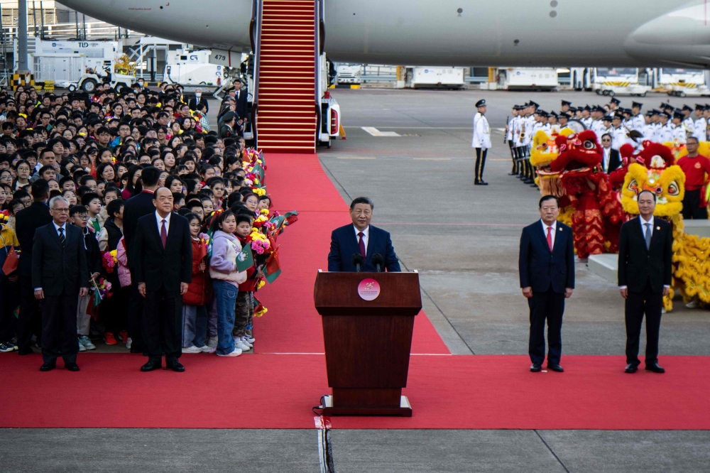 China's President Xi Jinping (C) speaks upon his arrival at Macau's international airport in Macau. — AFP