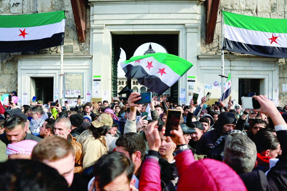A person holds the Syrian flag adopted by the new rulers as people attend Friday prayers in Damascus, Syria. — Reuters