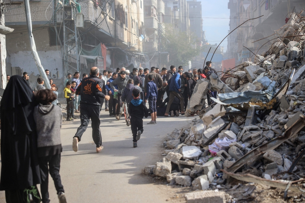 People rush to the aid of a man injured in an Israeli strike on the Bureij refugee camp in the central Gaza Strip. — AFP 