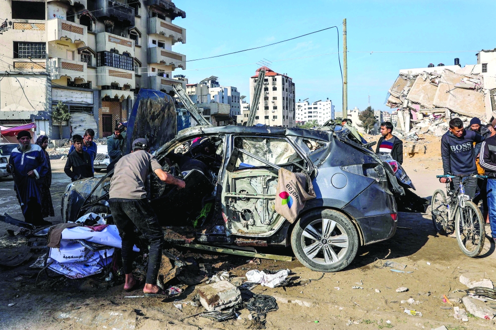 People inspect the remains of a civilian vehicle that was hit by Israeli bombardment along Jalaa Street in central Gaza City on Sunday. — AFP