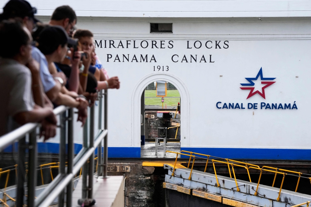 Tourists watch a cargo ship transit through the Panama Canal in Panama City. — AFP