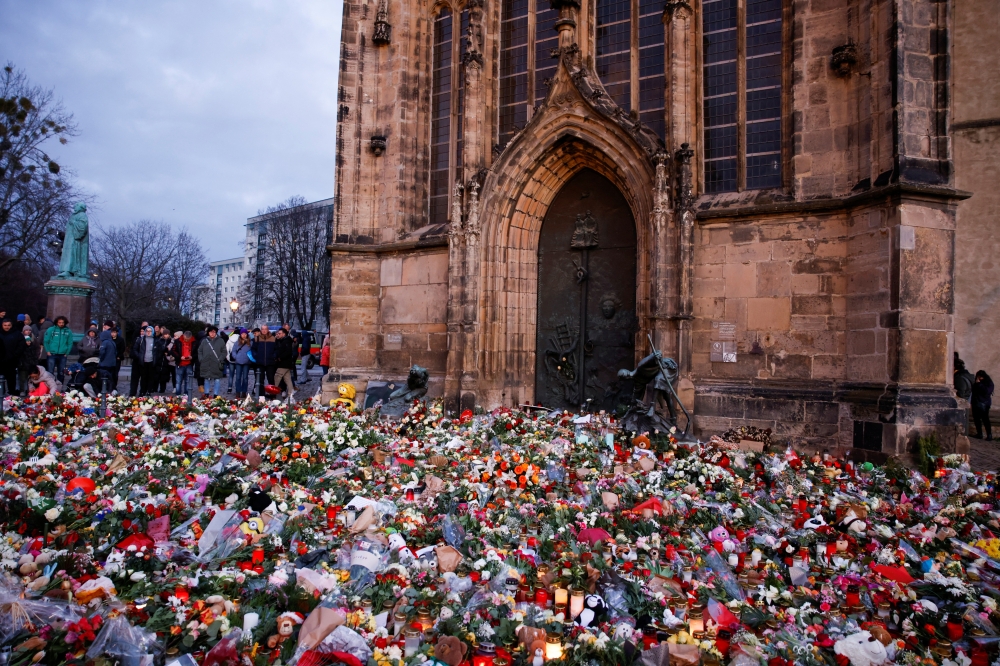People look at flowers and candles left as a tribute for the victims of the 'Alter Markt' Christmas market, in Magdeburg. — Reuters 