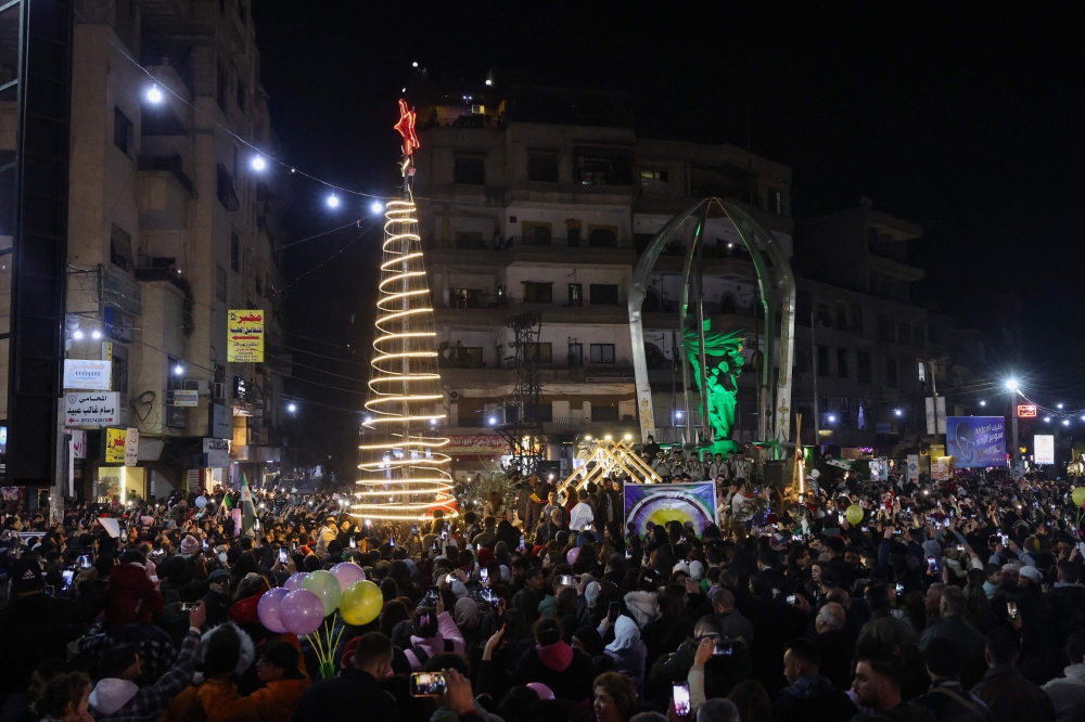 People celebrate the lighting of the Christmas tree in the Damascus countryside, Syria. — AFP