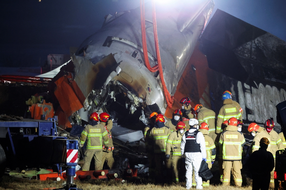Rescuers work the wreckage of an aircraft that went off the runway and crashed, at Muan International Airport, South Korea. — AFP 
