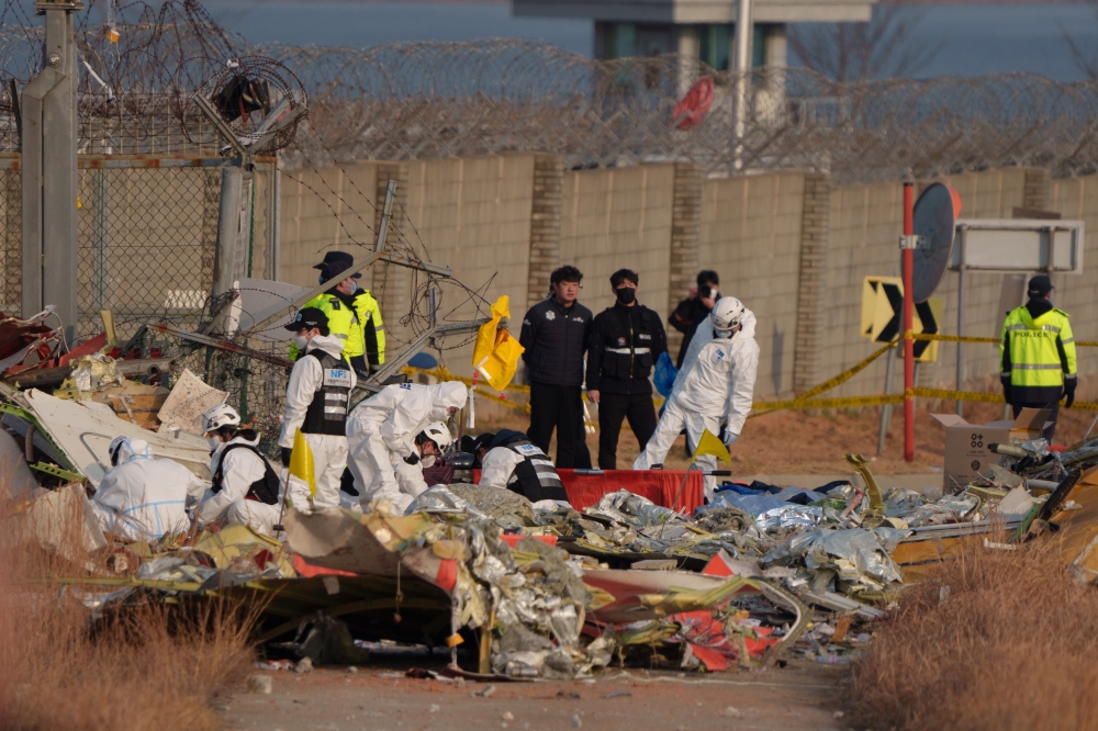 Firefighters and investigators at the scene of the Jeju Air passenger jet crash in Muan South Korea, Dec. 29, 2024. (Chang W. Lee/The New York Times)